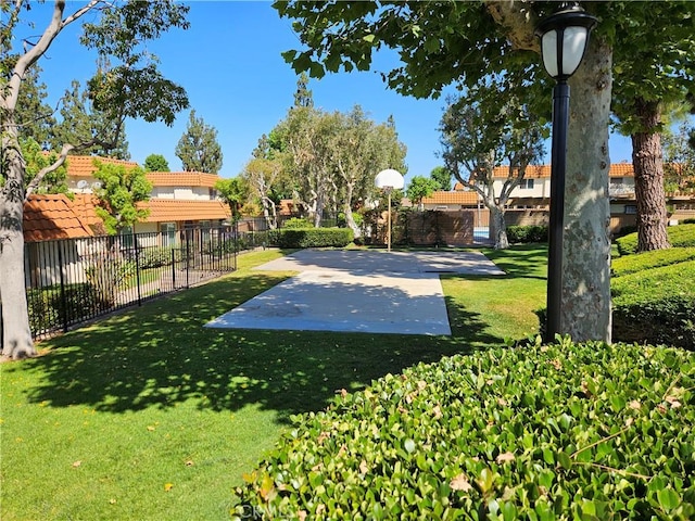 view of yard with fence and basketball court