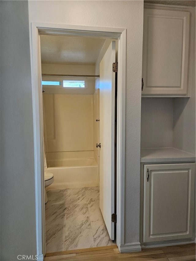 full bathroom featuring toilet, marble finish floor, and shower / bathing tub combination