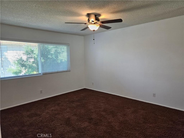 spare room featuring dark colored carpet, ceiling fan, and a textured ceiling