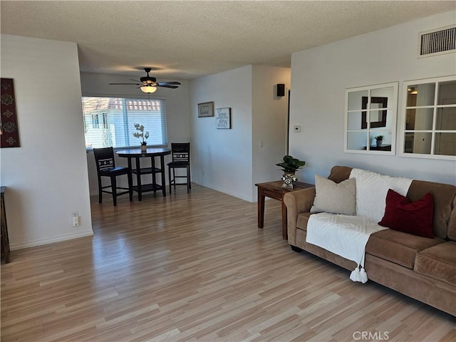 living area featuring a textured ceiling, light wood finished floors, and visible vents