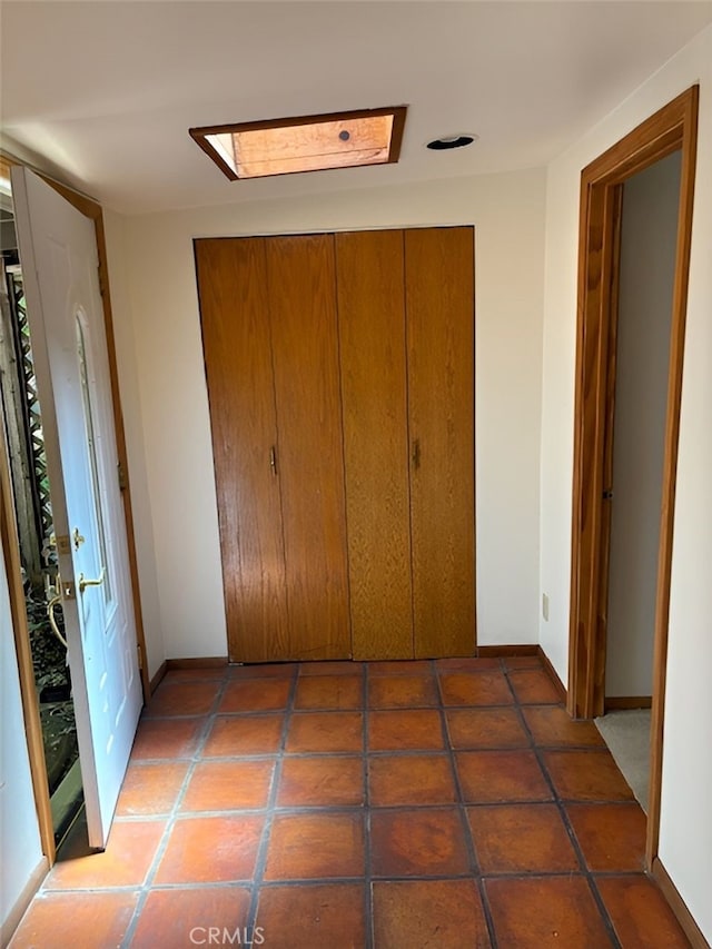 unfurnished bedroom featuring dark tile patterned flooring, a closet, and a skylight