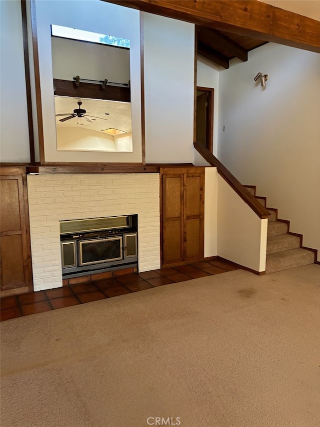 unfurnished living room with a fireplace, beam ceiling, ceiling fan, and dark carpet