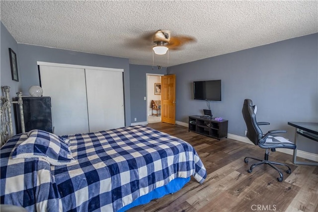 bedroom featuring ceiling fan, a closet, dark wood-type flooring, and a textured ceiling