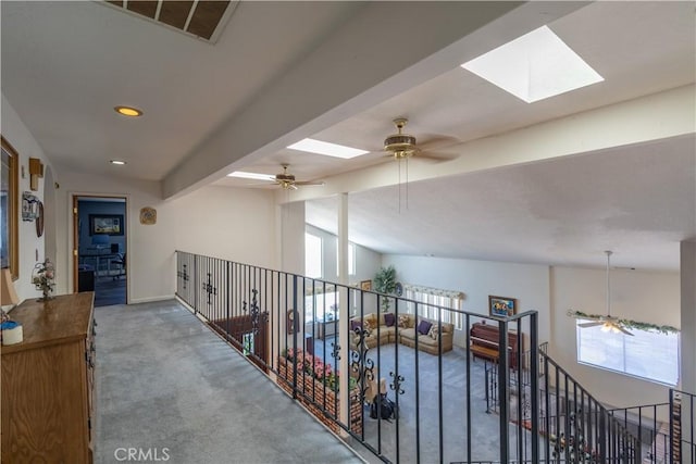 hallway with carpet floors and vaulted ceiling with skylight