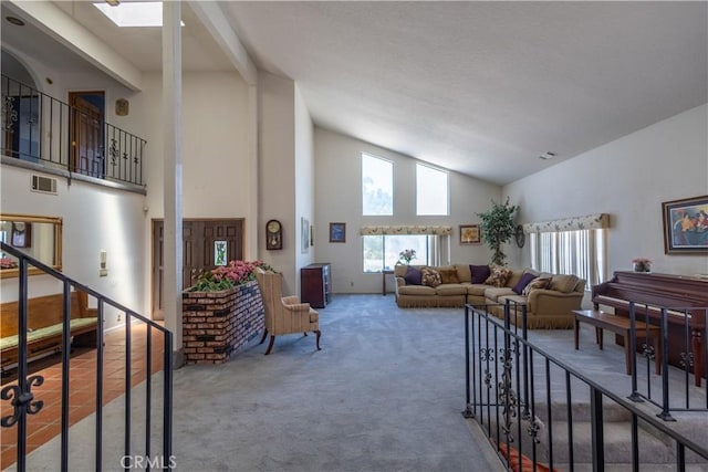 carpeted living room with high vaulted ceiling and a skylight