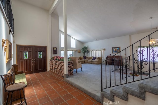 entrance foyer with ceiling fan, a high ceiling, and dark tile patterned floors