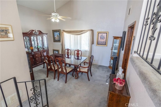 carpeted dining space with high vaulted ceiling and ceiling fan