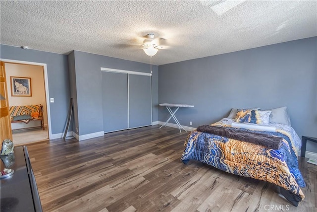 bedroom featuring dark wood-type flooring, ceiling fan, a closet, and a textured ceiling