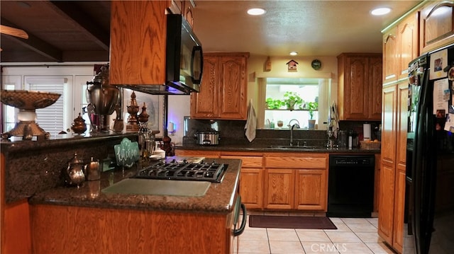 kitchen with backsplash, dark stone counters, black appliances, sink, and light tile patterned floors