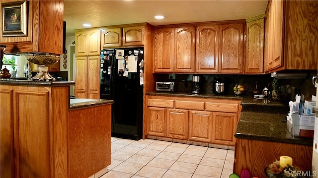 kitchen featuring black refrigerator, backsplash, and light tile patterned flooring