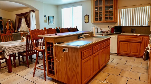 kitchen with dishwasher, light tile patterned floors, a kitchen island, and sink