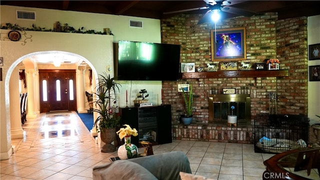 tiled living room featuring a brick fireplace and ceiling fan