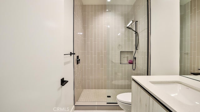 bathroom featuring tile patterned floors, vanity, a shower with shower door, and toilet