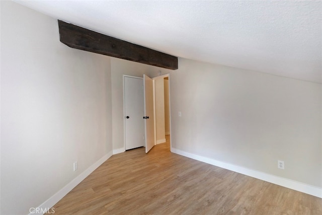 additional living space featuring beamed ceiling, light hardwood / wood-style floors, and a textured ceiling