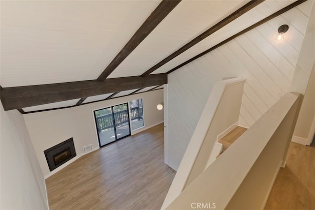 unfurnished living room with vaulted ceiling with beams and hardwood / wood-style floors