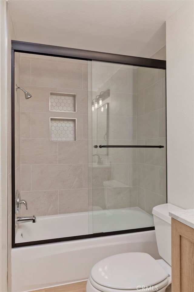 full bathroom with enclosed tub / shower combo, vanity, and toilet