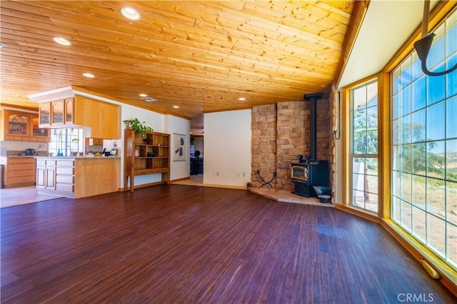 unfurnished living room featuring wood ceiling, a wood stove, a wealth of natural light, and dark wood-type flooring