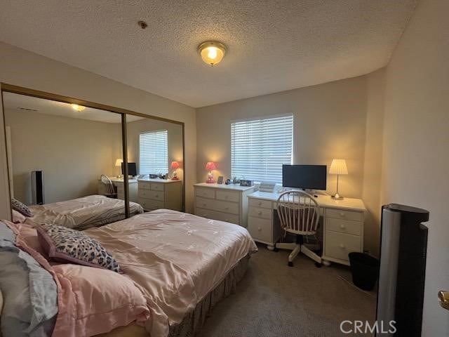 bedroom with a closet, a textured ceiling, and carpet