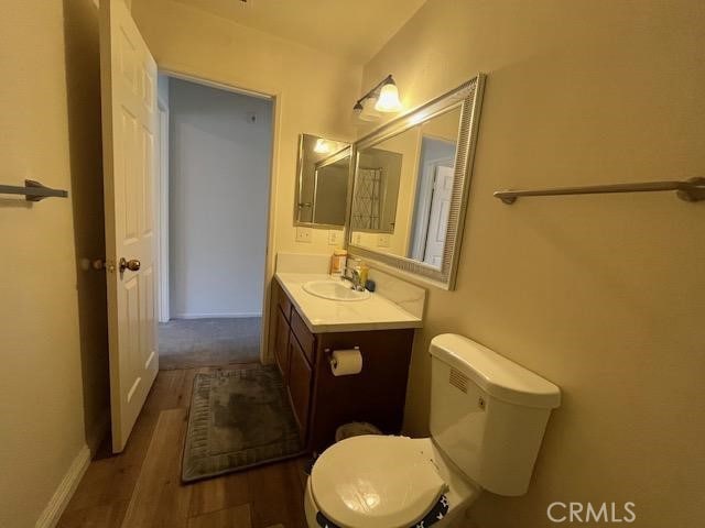 bathroom featuring toilet, hardwood / wood-style floors, and vanity