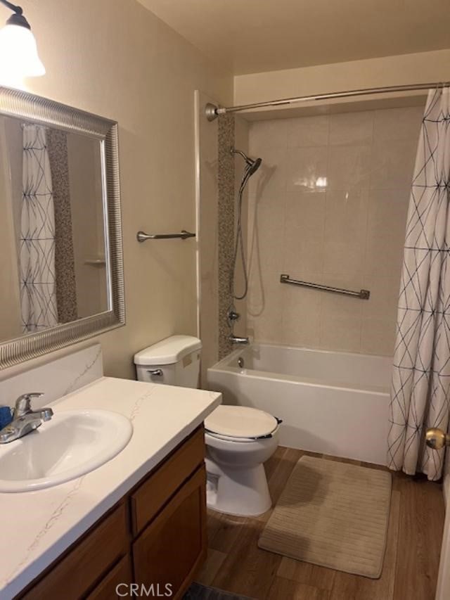 full bathroom with vanity, toilet, hardwood / wood-style flooring, and shower / bath combination with curtain