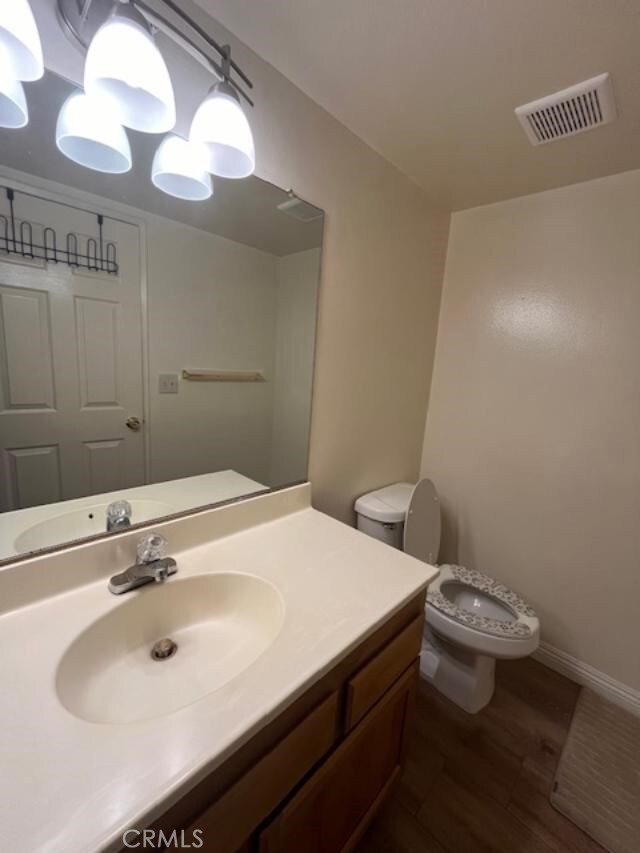 bathroom featuring vanity, hardwood / wood-style flooring, and toilet