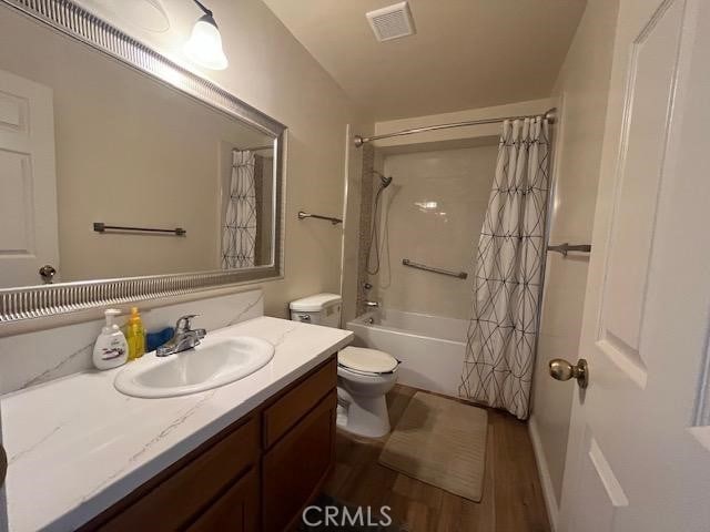 full bathroom with vanity, hardwood / wood-style floors, toilet, and shower / bathtub combination with curtain