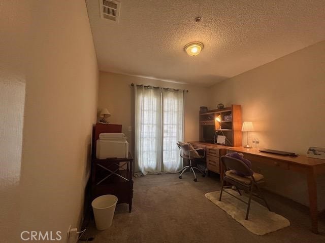 carpeted home office featuring a textured ceiling