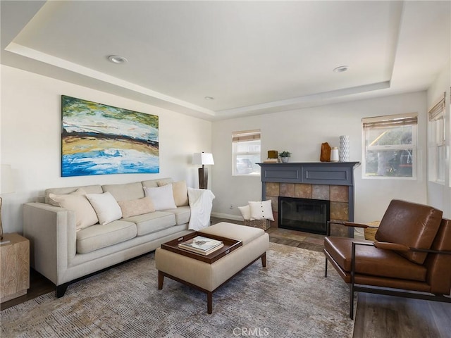 living room featuring hardwood / wood-style flooring, a raised ceiling, and a tile fireplace