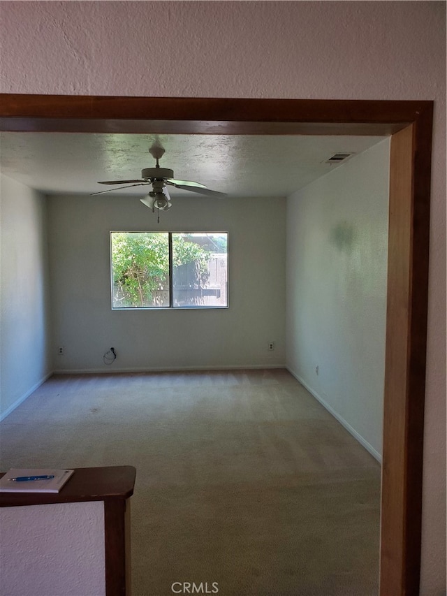 empty room featuring light carpet, a textured ceiling, vaulted ceiling, and ceiling fan