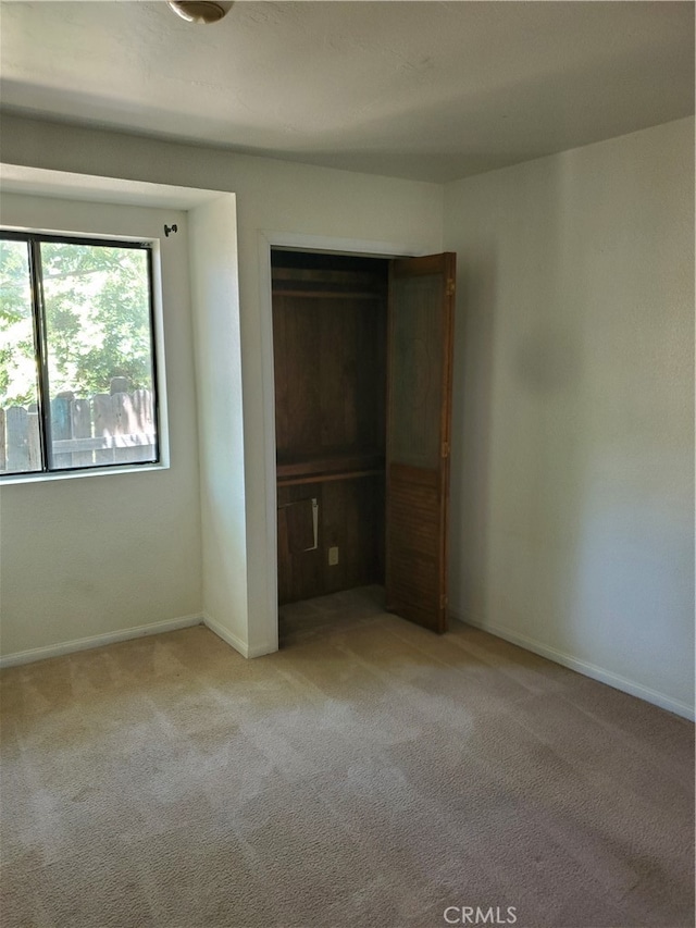 unfurnished bedroom with light carpet and a closet