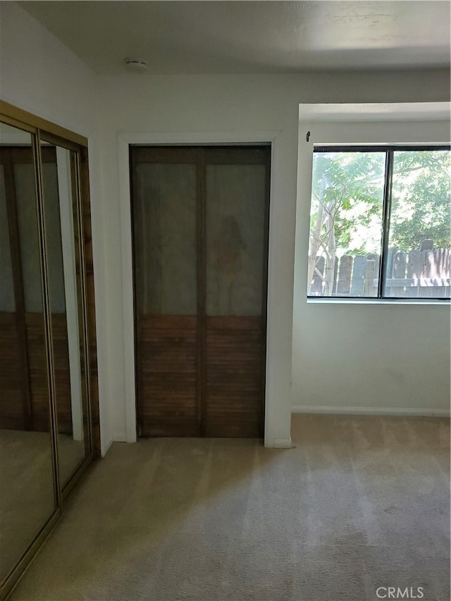 unfurnished bedroom featuring light colored carpet and two closets