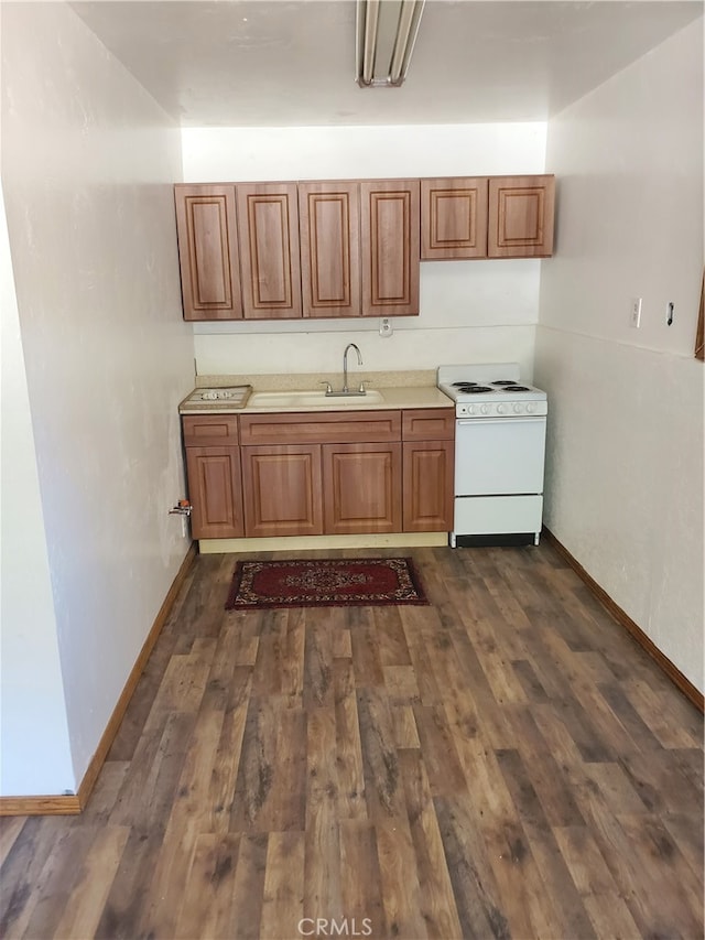 kitchen featuring dark hardwood / wood-style flooring, white range oven, and sink