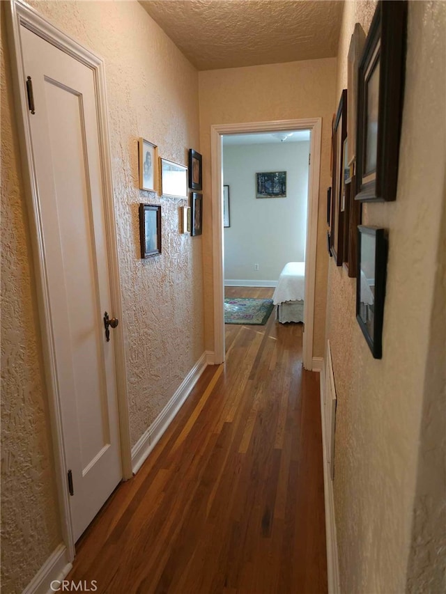 hall featuring a textured ceiling and dark hardwood / wood-style floors