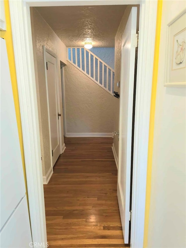 hallway with hardwood / wood-style floors and a textured ceiling