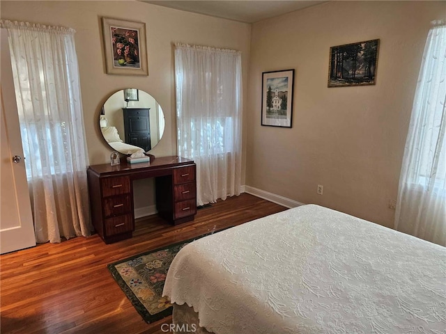 bedroom with dark hardwood / wood-style flooring and multiple windows