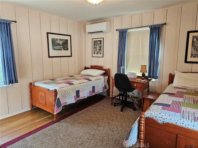 bedroom featuring a wall mounted air conditioner and hardwood / wood-style flooring