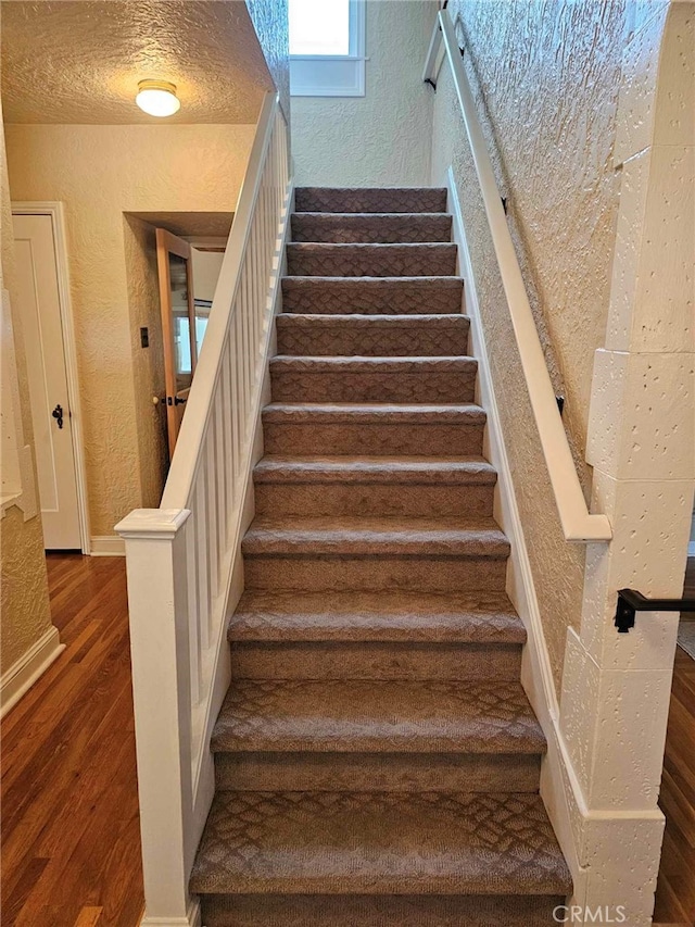 stairway featuring wood-type flooring and a textured ceiling