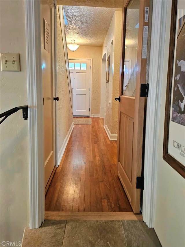 hallway featuring hardwood / wood-style floors and a textured ceiling