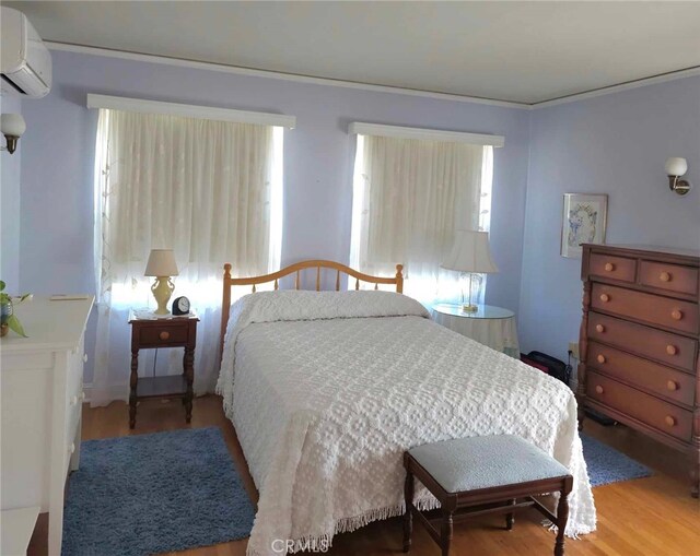 bedroom featuring hardwood / wood-style flooring and a wall mounted AC