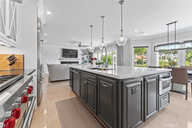 kitchen featuring ceiling fan, an island with sink, white cabinetry, sink, and decorative light fixtures