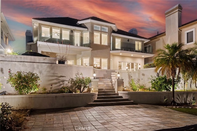 back house at dusk featuring a patio