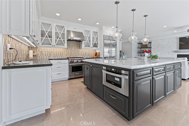 kitchen with exhaust hood, white cabinetry, a kitchen island with sink, crown molding, and high end appliances