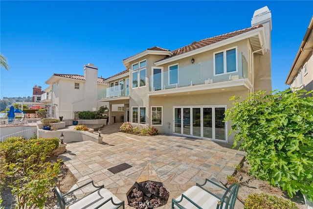 rear view of property with a patio area, an outdoor fire pit, and a balcony