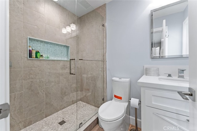 bathroom with toilet, vanity, and a shower with door