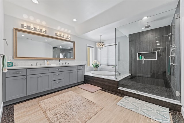 bathroom with vanity, a chandelier, hardwood / wood-style floors, and plus walk in shower