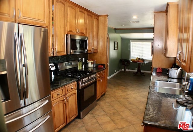 kitchen featuring stainless steel appliances, backsplash, dark stone counters, ornamental molding, and sink