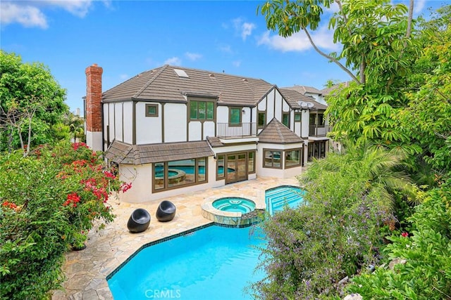 rear view of property with a pool with hot tub