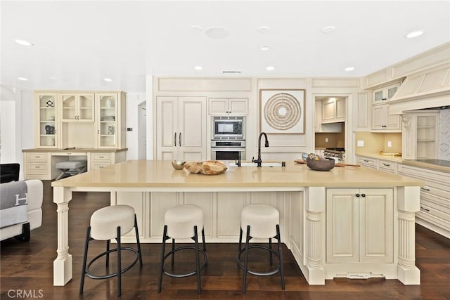 kitchen with cream cabinetry, a spacious island, dark hardwood / wood-style floors, and appliances with stainless steel finishes