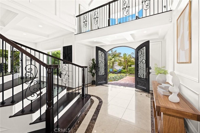 tiled foyer entrance featuring beamed ceiling, french doors, and coffered ceiling