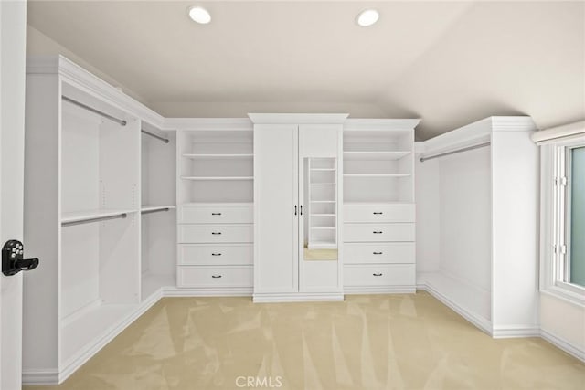 spacious closet with light colored carpet and vaulted ceiling